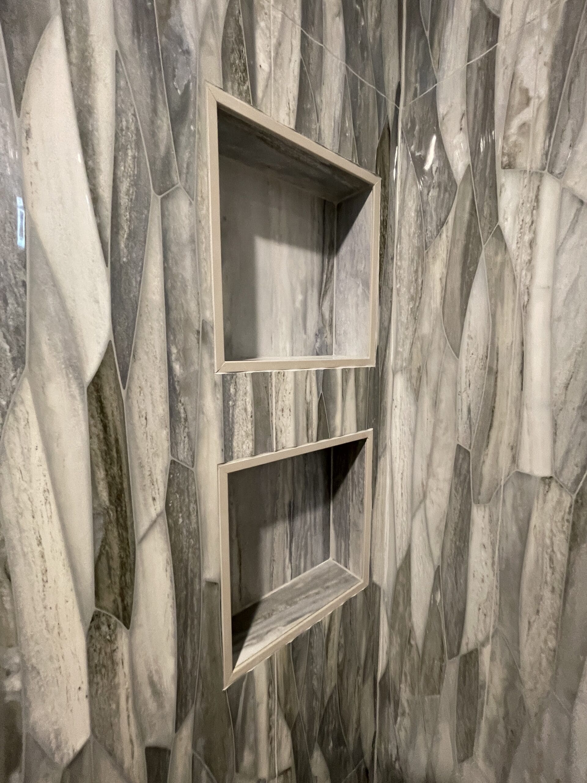 Double recessed shower niches in marble-look tile