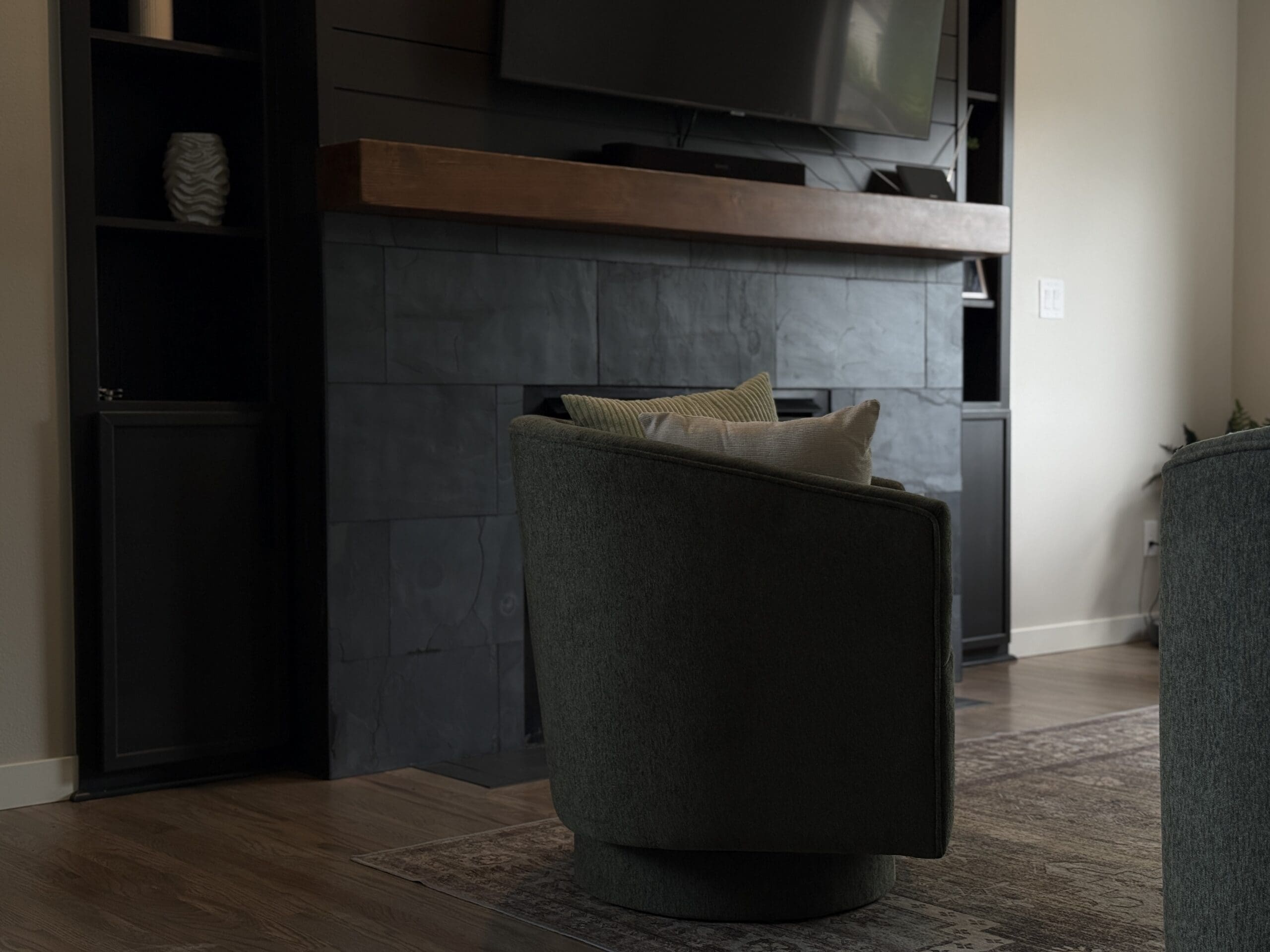 Modern fireplace surround in dark tile with wood mantel