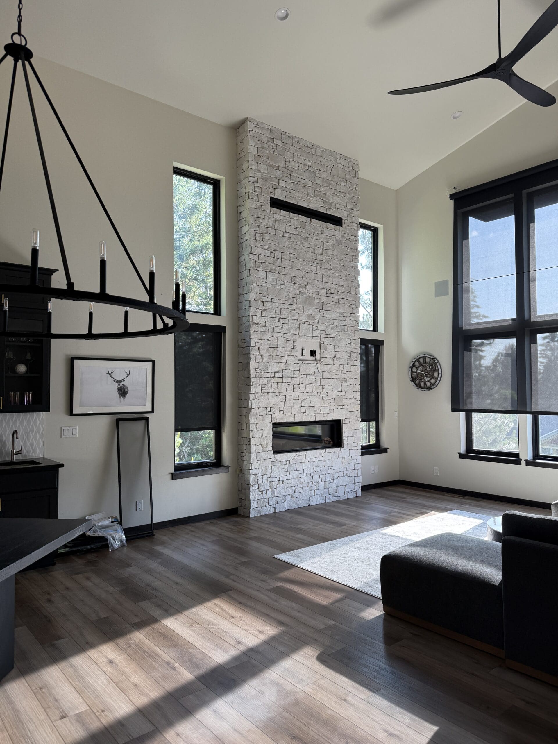Living room with a floor-to-ceiling stacked stone fireplace and large windows.