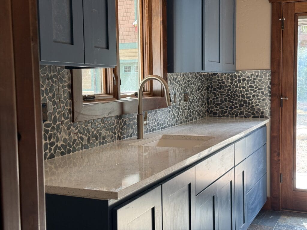 River rock backsplash and brushed gold vanity fixtures