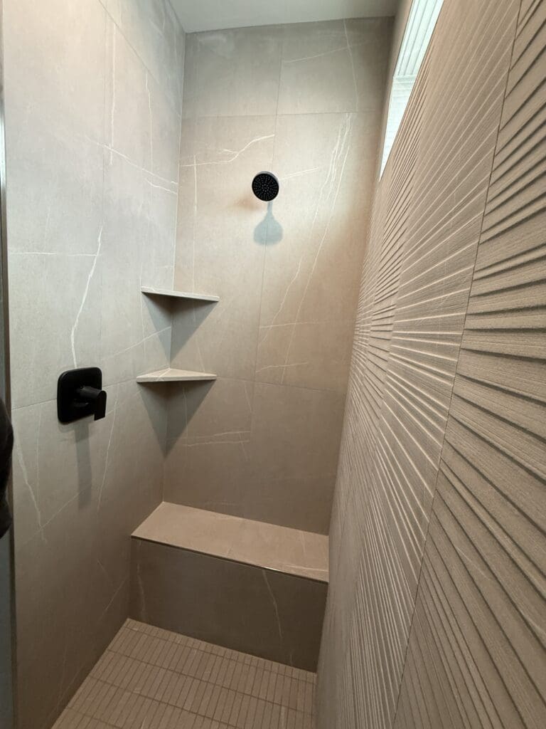 Textured feature tile and floating corner shelves in a walk-in shower